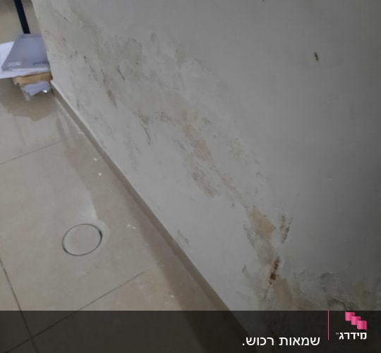 קיר עם סימני רטיבות ונזק, רצפה עם חור עגול